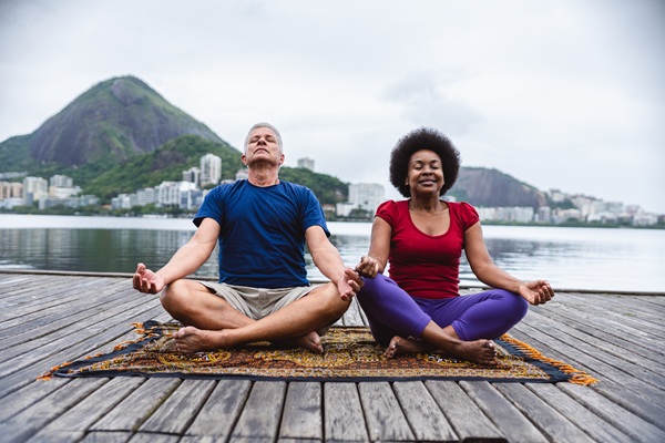 Couple practicing yoga near a lake