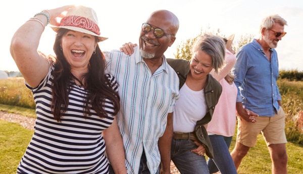 Five adult friends walking down a grass pathway