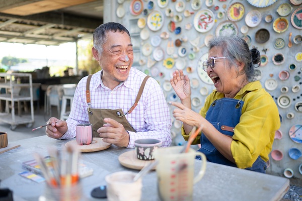 Older couple laughing while creating pottery together