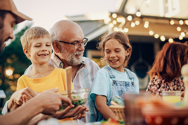grandpa sitting at a dinner with two grandchildren on his lap