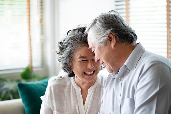 Older couple on a couch smiling at each other
