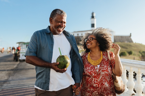 older couple smiling while walking together on a beach boardwalk